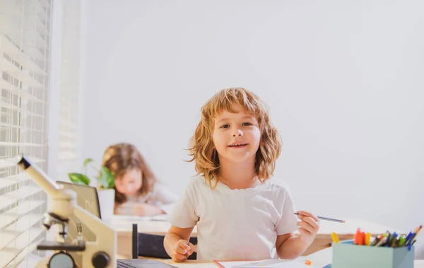 Vissza a suliba. Boldog aranyos gyerek ül egy íróasztalnál. Cild tanul az órán.. — Stock Fotó