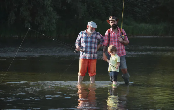 El abuelo y el padre con el niño lindo están pescando. Feliz día de los padres. Hombre hobby. Tres generaciones de edad: abuelo, padre e hijo adolescente joven. — Foto de Stock