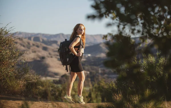 Wanderin mit Rucksack. Mädchen wandern einen Hügel hinauf und betrachten die atemberaubende und wilde Landschaft am Aussichtspunkt. Backpacking Tourismus Konzept Hintergrund. — Stockfoto