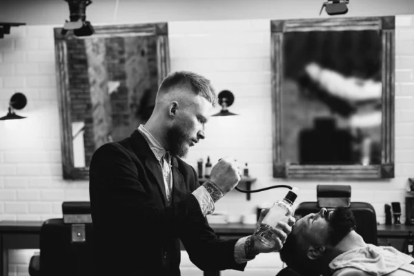 Lame de rasoir. Homme barbu se faire couper les cheveux par coiffeur et assis dans la chaise au salon de coiffure. Styliser avec le rasoir. Hommes après rasage. Produit cosmétique après-rasage. Les gars peau de visage . — Photo