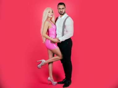 Pembeye izole edilmiş birkaç oyuncak bebek. Pembe elbiseli romantik moda kadını ve takım elbiseli şık bir adam..