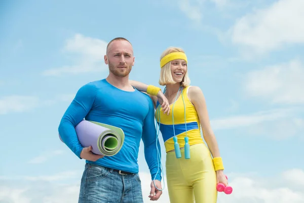 Fitness uomo e donna in allenamento. Giovane coppia felice in fasce con manubri e tappetino fitness all'aperto. — Foto Stock