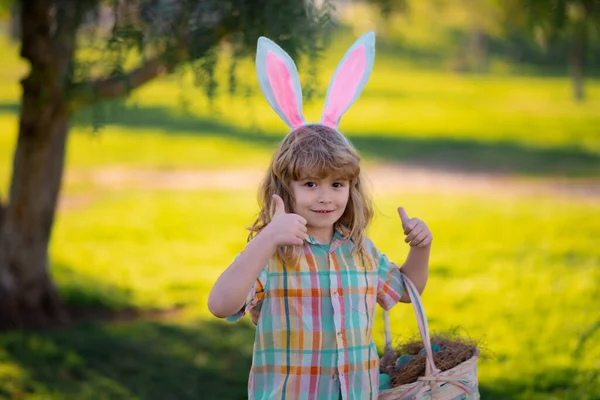 Mutlu Paskalyalar. Paskalya yumurtası avlayan çocuk. Tavşan kulaklı şirin çocuk parkta paskalya geçiriyor. Çocuklar paskalya yumurtası avlar.. — Stok fotoğraf