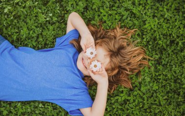 Mutlu küçük çocuk bahar günü çimlerin üzerinde yatıyor..