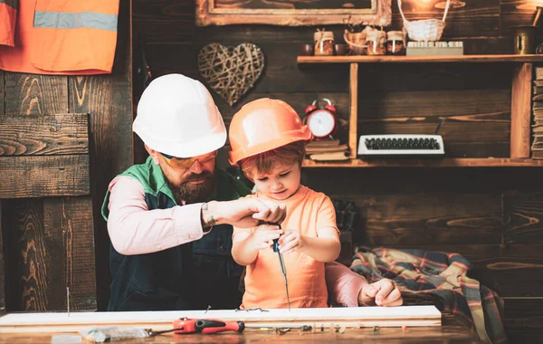 Vader en zoon aan het repareren in de werkplaats. Kind met timmermansgereedschap in houtwerk. — Stockfoto