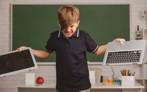 不良少年学生対遠隔教育。怒っている子供は学校でオンラインノートパソコンを壊した。損傷したコンピュータ技術を粉砕する。遠隔学習の子供の問題. — ストック写真