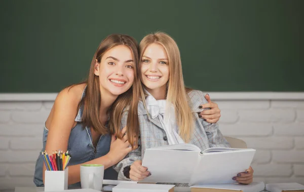 Šťastní usměvaví studenti dívky objímání a objímání ve třídě na vysoké škole. — Stock fotografie