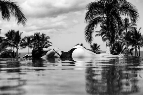 Πολυτελές θέρετρο. Σέξι γυναίκα χαλαρώνει στην πισίνα του απείρου. Όμορφο μοντέλο που απολαμβάνει καλοκαιρινές διακοπές, με θέα στη θάλασσα. Θερινή ώρα αναψυχή. — Φωτογραφία Αρχείου