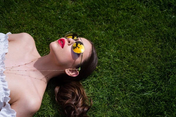 Portret van een jonge vrouw in een zonnebril buiten op gras. Romantisch meisje met schoonheid gezicht. — Stockfoto