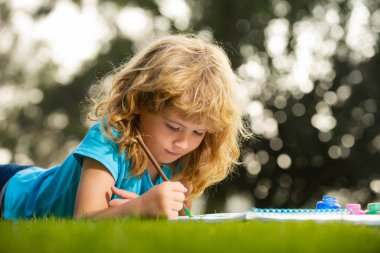 Okul çocukları yaz parkında resim çiziyor, resim yapıyor. Küçük ressam açık havada resimler çizer..