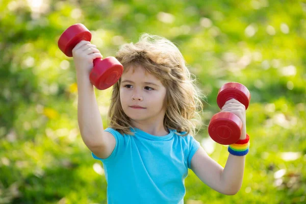 Barn morgon sport övningar. Ungar sport. Sportaktiviteter på fritiden med barn utomhus. Vacker blond pojke som håller hantlar i parken. — Stockfoto