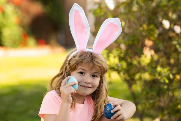 Niño cazando huevos de Pascua. Niño con huevos de Pascua y orejas de conejo al aire libre. Vacaciones de Pascua. —  Fotos de Stock