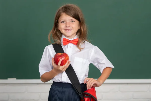 Porträtt av vackra flicka sanningen rött äpple i klassrummet. Begreppet utbildning, lärande och barn. — Stockfoto