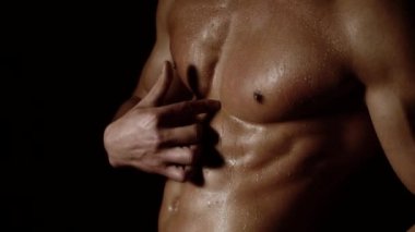 Güçlü atletik adam kaslı vücut ve siyah arka planda karın kasları gösteriyor. Seksi çıplak gövde, karın kası. Erkek kaslarını esnetiyor. Mükemmel karın kaslarına yaklaş. Altılı paketli güçlü vücut geliştirici..