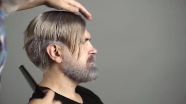 Kuaför, erkek modellerin saçlarına renkli renkler sürüyor. Reklamcılık ve berber dükkanı konsepti. Profesyonel kuaför. Güzellik salonunda erkek saçı tarıyor. Yakın plan..