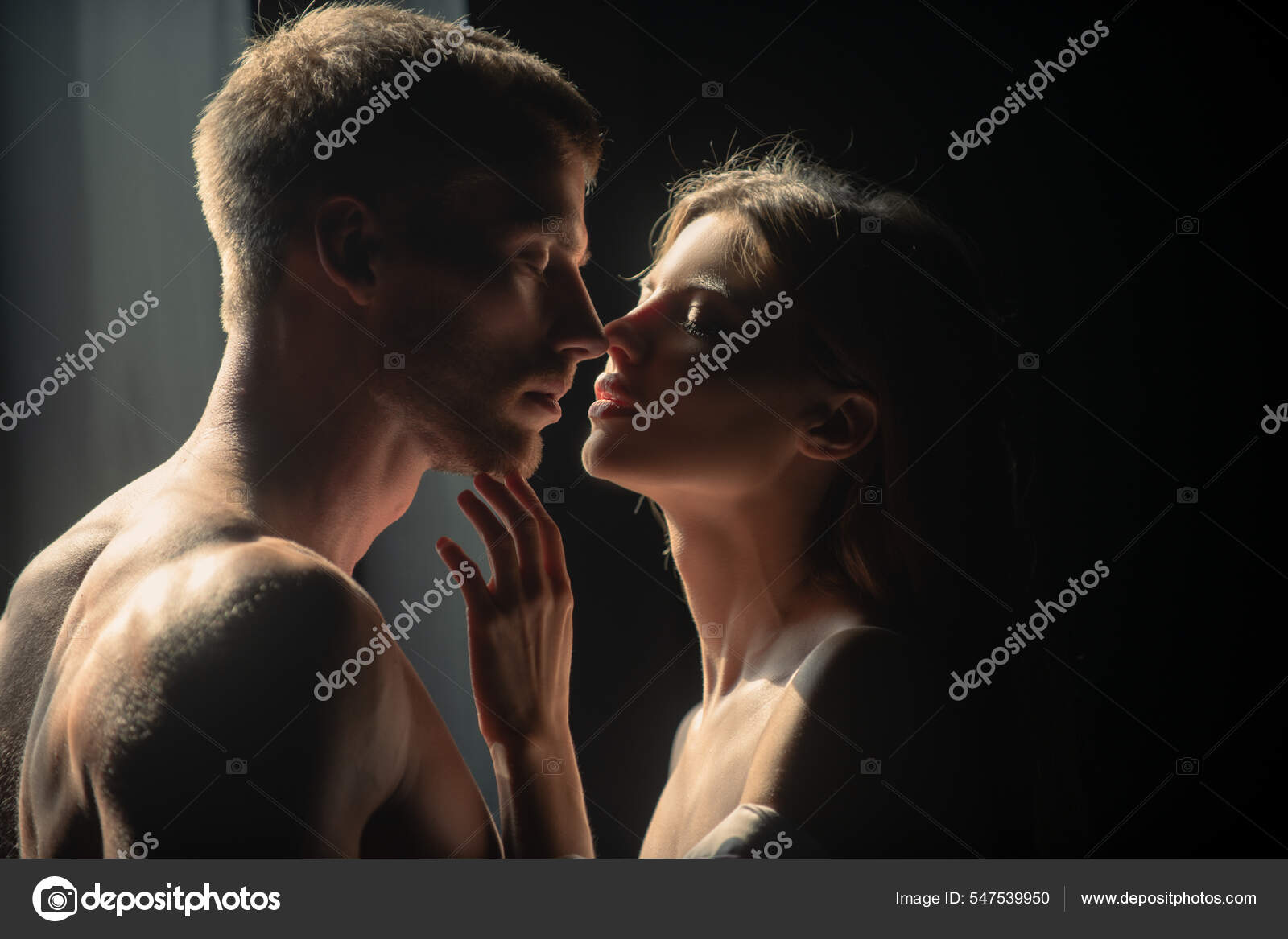 Beautiful loving couple posing on dark backgroung with night lights. Man embracing and going to kiss sensual woman