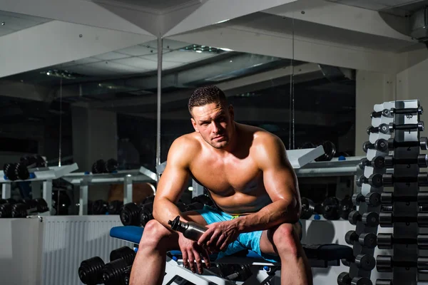 Uomo muscolare Ritratto di uomo atletico riposo con bottiglia di proteine. Un giovanotto che si allena in palestra. Atletico ragazzo facendo esercizio. — Foto Stock