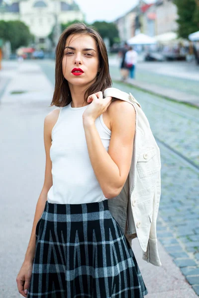 Modelo feminino bonita segurar o terno branco através de sholder na cidade de verão na Europa. Mulher na moda posando no fundo da rua. — Fotografia de Stock