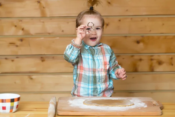 台所の小さなパン職人の子供。幸せな赤ん坊の子供のベーキングクッキー。台所で手作りのパン屋をやっている子供のかわいい赤ちゃん。テーブルに座って料理やベーキングを学ぶ子供. — ストック写真