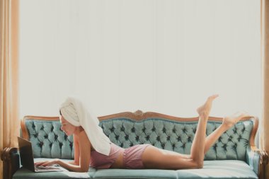 Kaygısız kadın model, yatakta bilgisayar kullanan şehvetli bir kadın. Sabah serinliği.