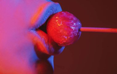 Şekerli seksi dudaklar, seksi tatlı rüyalar. Oral seks konsepti. Dişi ağız chupa chup yalıyor, lolipop emiyor. Neon ışıkları. Gece kulübü geçmişi.