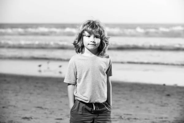 Χαριτωμένο αγόρι περπατώντας στην παραλία με το χέρι στην τσέπη. — Φωτογραφία Αρχείου