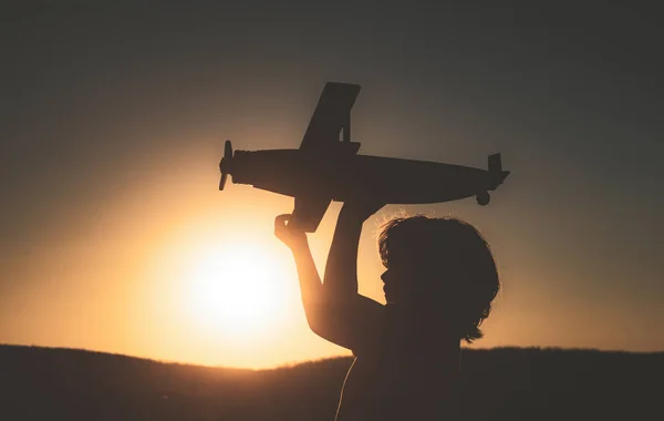 Aviador piloto infantil con juguete avión sueña con viajar en verano en la naturaleza al atardecer . — Foto de Stock