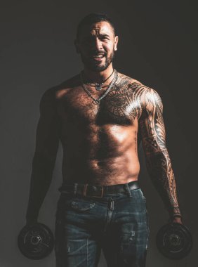 Güçlü yakışıklı sporcu halter kaldırıyor ve halterle kaslarını çalıştırıyor..