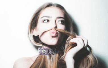 Genç oyuncu kız saçıyla bıyık yapıyor. Flört etmek, romantik kadın ve baştan çıkaran kız. Güzel kız, güzel sarışın kadın saçı.