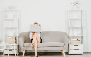 Genç çekici seksi sekreter ofiste. Güzel sekreter bacakları. Dizüstü bilgisayarı ve seksi bacakları olan baştan çıkarıcı seksi sekreter ofiste koltukta oturuyor. Şehvetli genç kız çalışan..