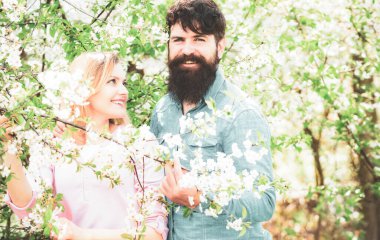 Mutlu Paskalyalar. Çiçek ağacının yanında genç mutlu bir çift. Aşıklar baharda çiçek açan parkta yürür.