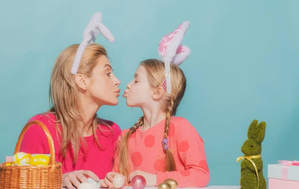 Приваблива молода жінка з маленькою милою дівчинкою готується до Великодня. Мати і дочка в вухах кролика цілуються, проводячи час разом перед Великоднем під час фарбування яєць . — стокове фото