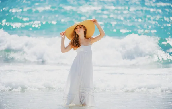 Sensuelle fille avec chapeau de paille profitant d'un bain de soleil à la plage. Sexy femme bronzée profitant de la brise au bord de la mer. Femme insouciante souriant avec océan de mer en arrière-plan. — Photo