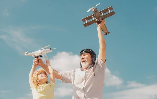 Vieux grand-père et petit-fils enfant avec avion jetpack jouet et drone quadcopter contre le ciel. Enfant pilote aviateur avec des rêves d'avion de voyager. — Photo
