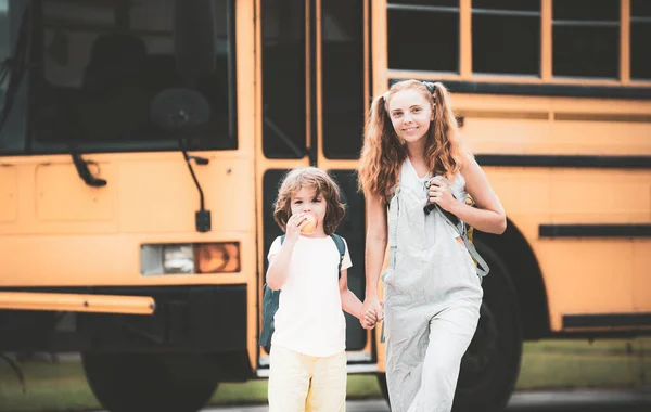 Grundschüler im Schulbus. Wenig bereit zum Studium. Glückliches Geschwisterpaar steht gemeinsam vor Schulbus. — Stockfoto