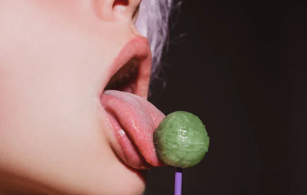 Licking tongue lips. Girl with sexy mouth eating chupa chups close up. Woman lips sucking lollypop. Woman holding lollipop in mouth, close up. Red lips, sensual and sexy concept. — Stock Photo, Image