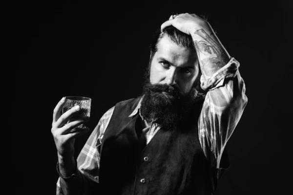 Empresario barbudo en traje elegante con vaso de whisky. Bebiendo whisky. Hombre guapo barbudo sosteniendo un vaso de whisky . — Foto de Stock