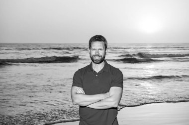 Denizde ya da okyanusta yakışıklı bir adam. Seyahat tatili. Denizde yürüyen adam, tropikal mevsimin tadını çıkar. Gün batımında Kafkasyalı yetişkinler gibi rahatla..