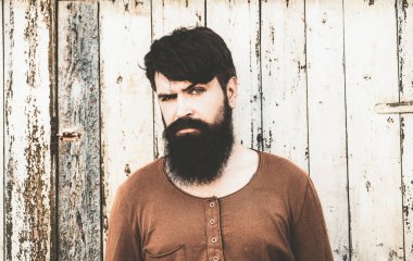 Sakallı, uzun sakallı ve tahta arka planda bıyıklı adam. Erkek ciddi yüz..