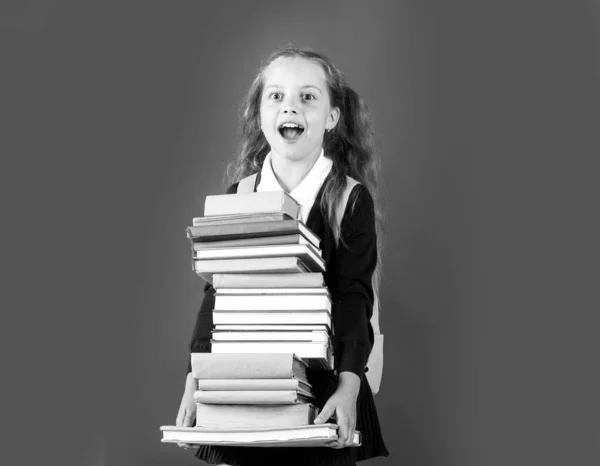 Wissenstag, Lächelndes lustiges kleines Schulmädchen mit Rucksack hält Bücher an grüne Tafel. Lebensstil in der Kindheit. Bildung in der Schule. — Stockfoto