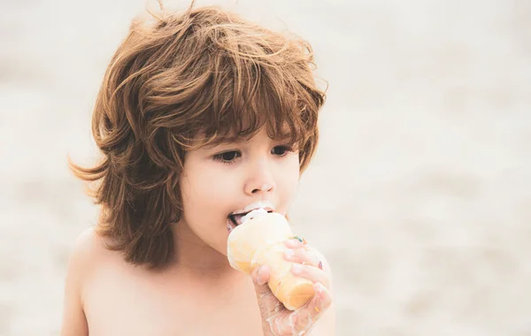 Ребенок ест мороженое. Парень с грязным лицом ест мороженое. — стоковое фото