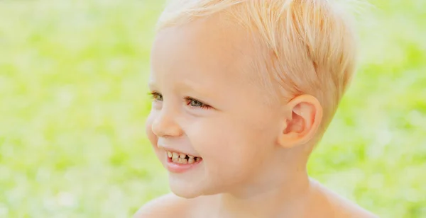 Leuke kinderen gezicht. Close-up portret van lachende jongen op groene achtergrond. Een glimlach. Emotieconcept. — Stockfoto