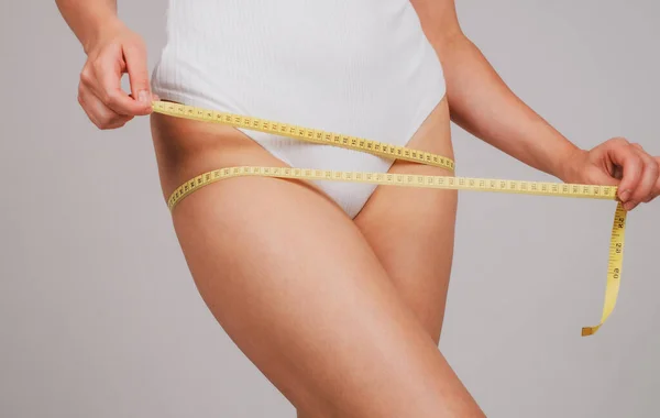 Jonge slanke vrouw meet haar middel door billen tape na dieet. Begrip gewichtsverlies. — Stockfoto