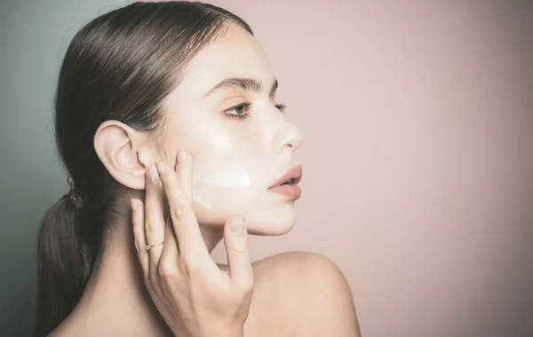 Mantenga la piel hidratada crema hidratante regularmente. Cuidando bien su piel. Hermosa mujer esparciendo crema en su cara. Crema para la piel. Cuidado facial para la mujer. Concepto de piel sana fresca —  Fotos de Stock