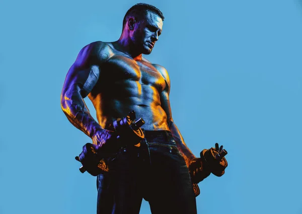 Een spieropbouwer die oefeningen doet met halters geïsoleerd op blauwe neon. Een fitnessman. Knappe jonge gespierde blanke bink traint armen op geïsoleerde blauwe achtergrond. — Stockfoto