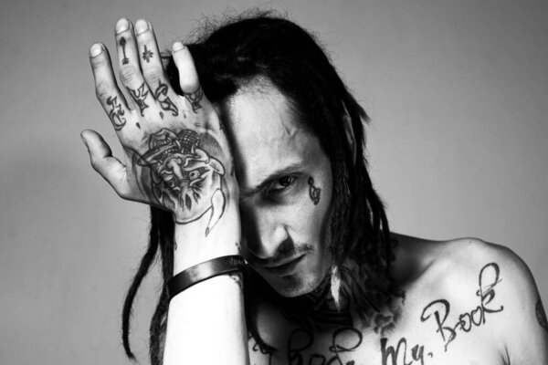 Portrait of handsome man with serious face. Tattooed and elegant hipster. Hippie guy.