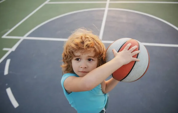 Aktywny styl życia dzieci. Mały biały sportowe dziecko gra w koszykówkę trzymając piłkę ze szczęśliwą twarzą. — Zdjęcie stockowe