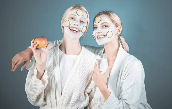 Meninas amigas irmãs fazendo máscara facial de barro. Máscara anti idade. Fica bonita. Cuidados da pele para todas as idades. Mulheres se divertindo máscara de pele de pepino. Beba água coma frutas. Conceito de saúde. Spa e bem-estar — Fotografia de Stock