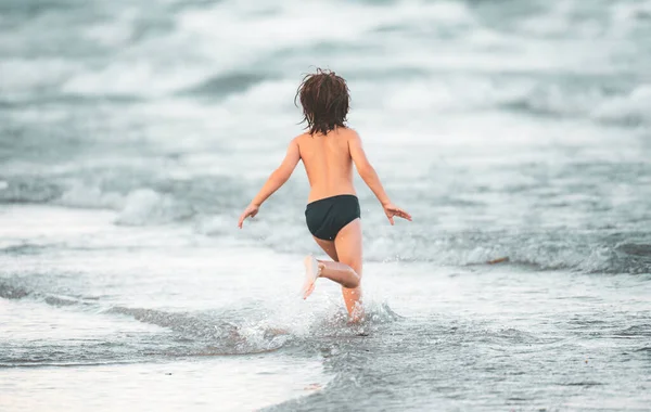 Feliz niño corriendo en el mar. Niño divirtiéndose en la playa. Vacaciones de verano y niños sanos. — Foto de Stock