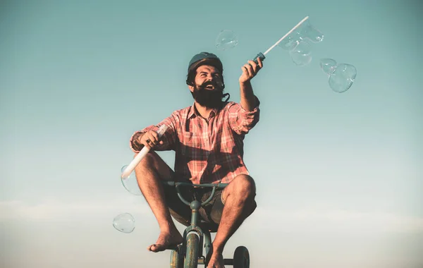 Memoria d'infanzia. Ritratto di un uomo barbuto come un hipster pazzo che si diverte con la bicicletta all'aperto. — Foto Stock
